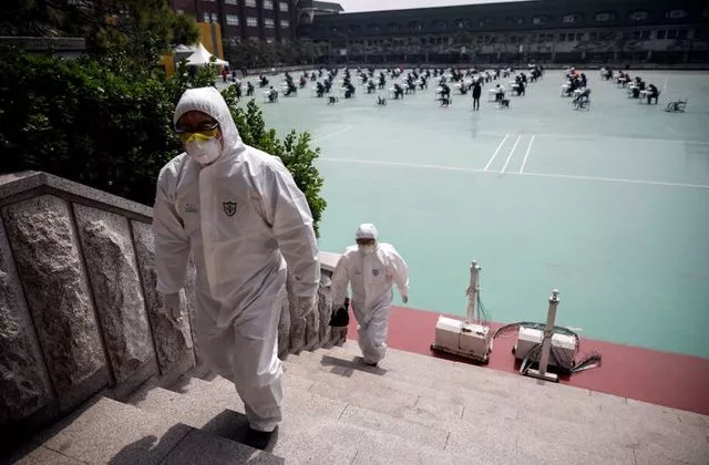 people in personal protective equipment walk up a flight of stairs as south korean job seekers background attend an exam conducted outdoors amid social distancing measures to avoid the spread of the coronavirus disease covid 19 in seoul south korea april 25 2020 photo reuters people in personal protective equipment walk up a flight of stairs as south korean job seekers background attend an exam conducted outdoors amid social distancing measures to avoid the spread of the coronavirus disease covid 19 in seoul south korea april 25 2020 photo reuters