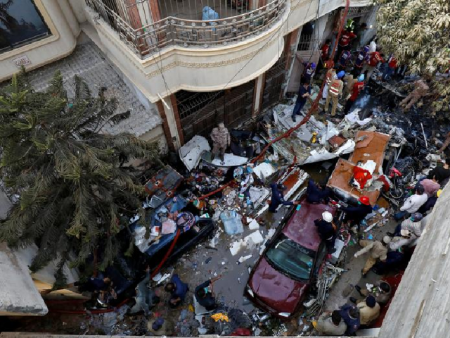 Rescue workers gather at the site of a passenger plane crash in a residential area near an airport in Karachi. PHOTO: REUTERS