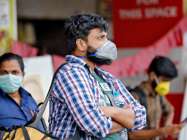 people wearing protective masks wait to board a bus at a terminal amid coronavirus fears in kochi india photo reuters file
