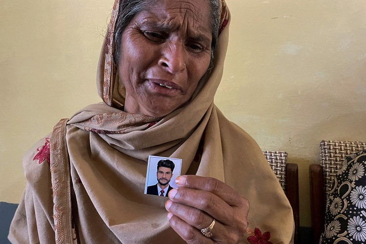 tazeem pervaiz mother of migrant taquir pervaiz who is missing after an overloaded trawler capsized and sank in the ionian sea weeps while holding a picture of her son in ajk bandli village photo afp