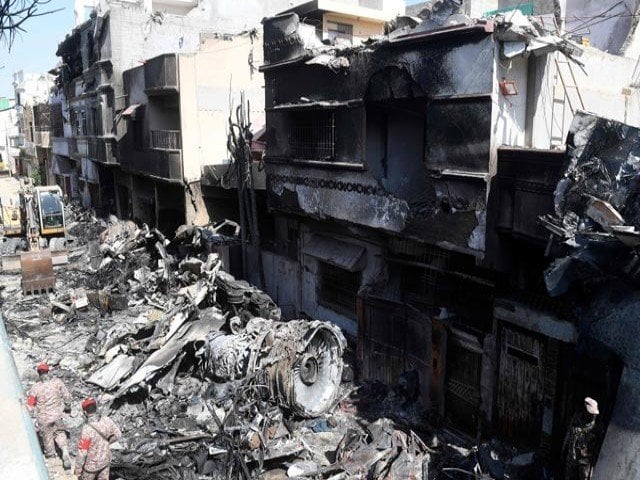 security personnel walk beside the wreckage of the crashed pia plane photo afp