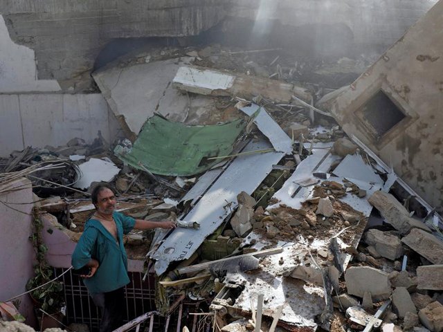 a man stands on the debris of a house at the site of a passenger plane crash in a residential area near airport in karachi photo reuters file