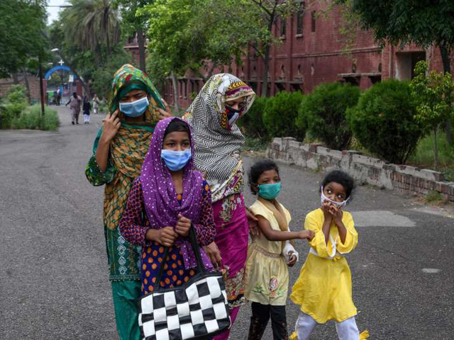 a catholic family wearing facemasks arrives to attend sunday prayers at the mary immaculate church in lahore photo afp file