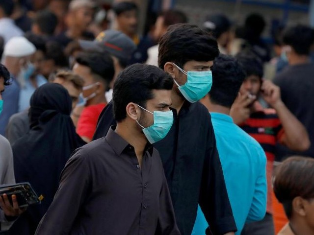 men wearing protective face masks walk amid the rush of people outside a market as the outbreak of the coronavirus disease covid 19 continues in karachi photo reuters