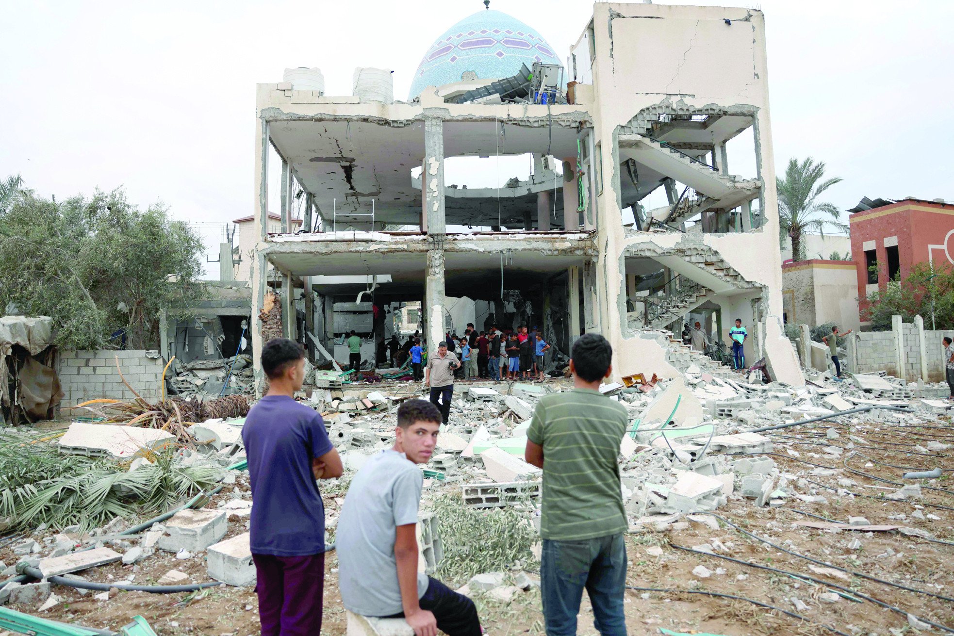 palestinians stare at a mosque turned shelter in deir al balah in the central gaza strip heavily damaged in an israeli strike photo afp