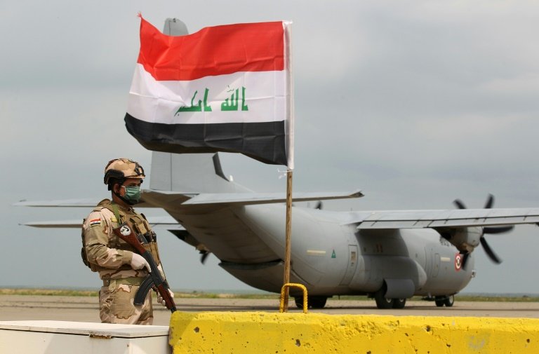 an iraqi soldier stands guard in front of a us military air carrier at the qayyarah air base near mosul in northern iraq on march 26 2020 the us says it will reduce troops in the country quot over coming months quot photo afp