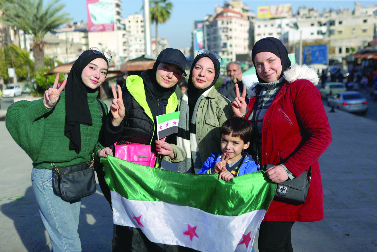 syrians pose with the opposition flag at a street in the coastal syrian city of latakia photo afp