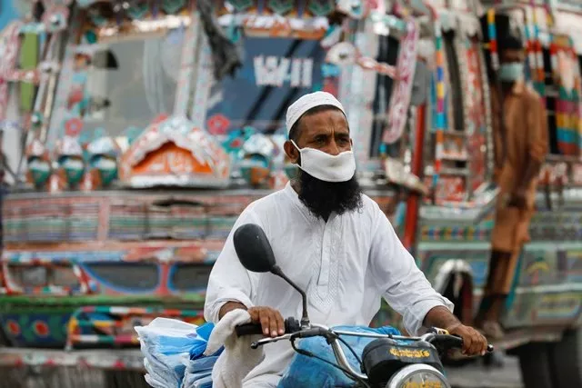 a man wearing a protective face mask rides a motorbike as the outbreak of the coronavirus disease covid 19 continues in karachi photo reuters