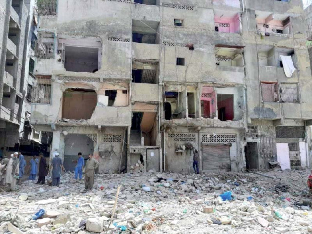 residents stand amid the debris of the apartment building that collapsed in lyari on june 7 killing 22 people photo express residents stand amid the debris of the apartment building that collapsed in lyari on june 7 killing 22 people photo express