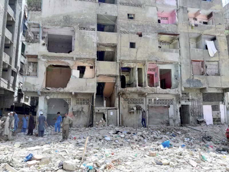 residents stand amid the debris of the apartment building that collapsed in lyari on june 7 killing 22 people photo express