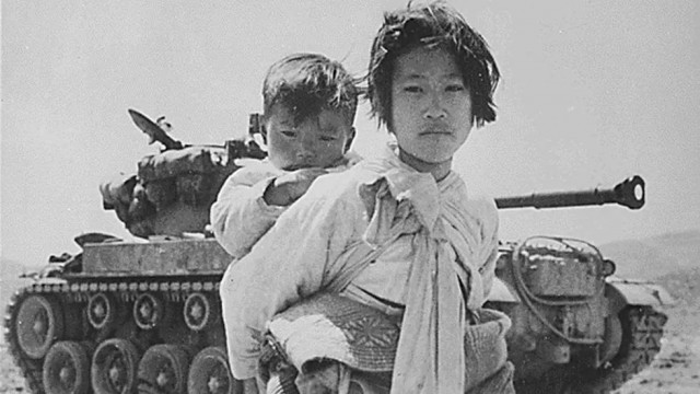 a young girl with her brother on her back walks past a stalled m 26 tank at haengju korea in june 1951 photo afp