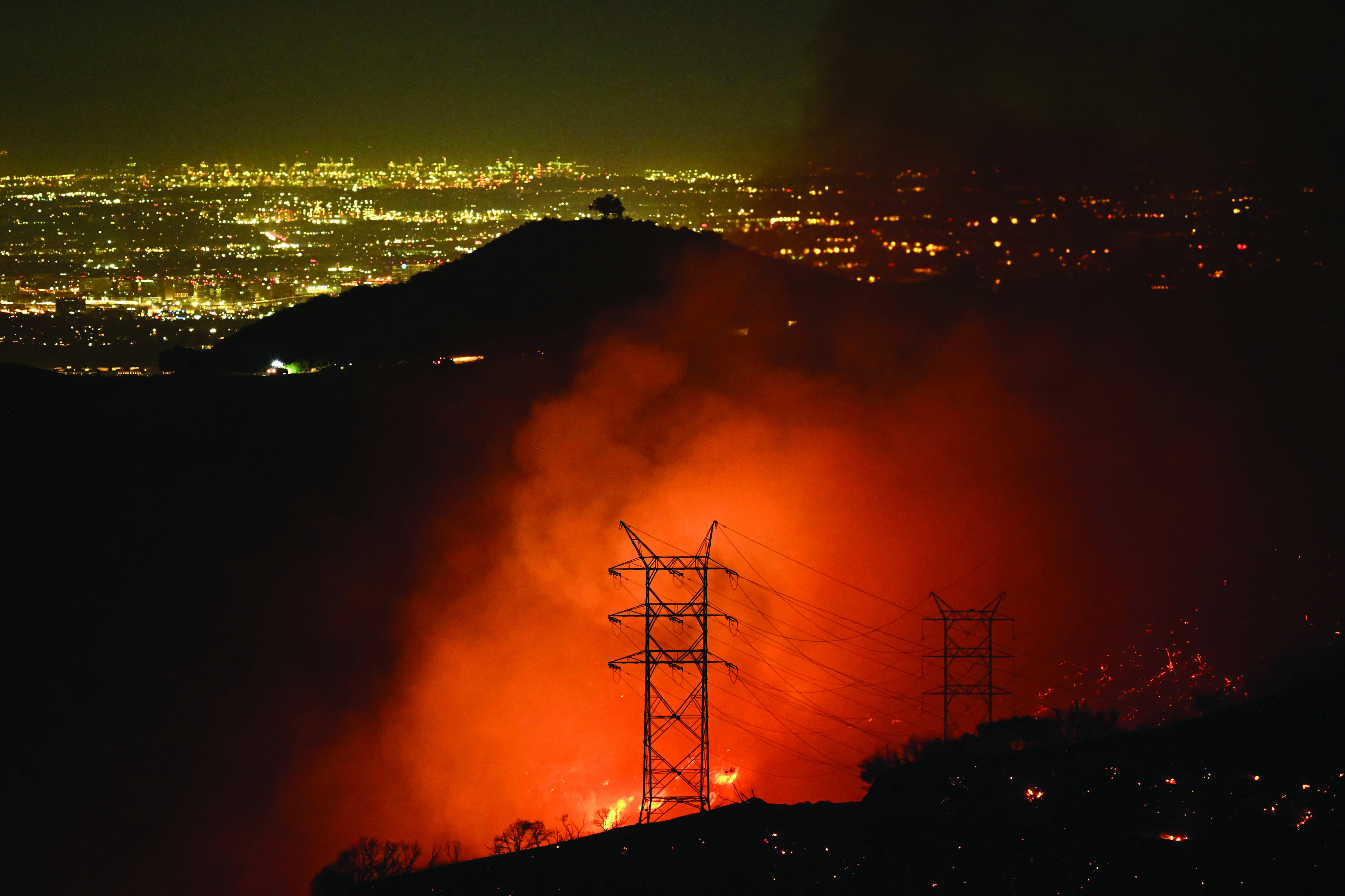 flames and smoke are seen near power lines as the palisades fire grows near the mandeville canyon neighborhood and encino california photo afp