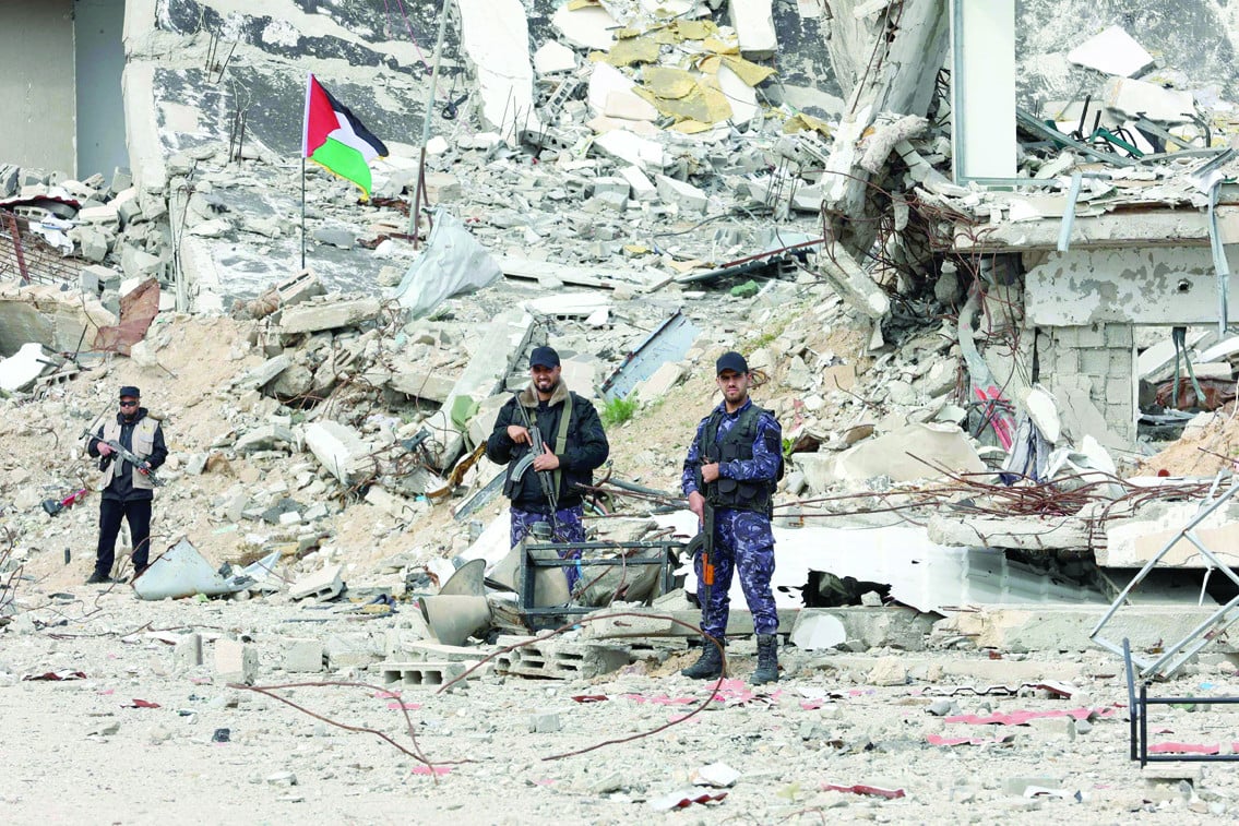 members of palestinian security forces loyal to hamas stand guard in front of a destroyed police compound in gaza city photo afp