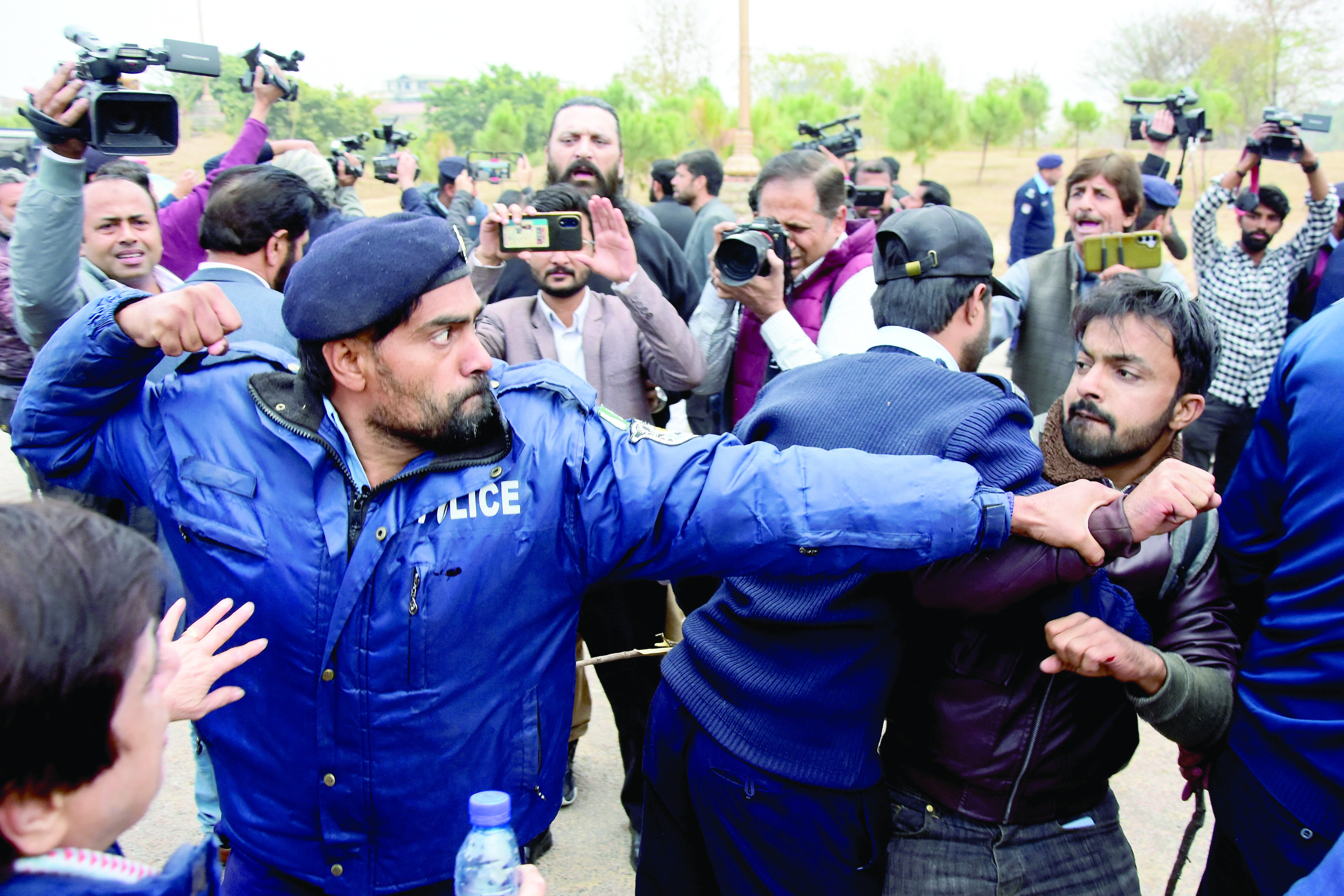 a policeman reacts while stopping a journalist who along with others is protesting against the peca bill in islamabad photo reuters