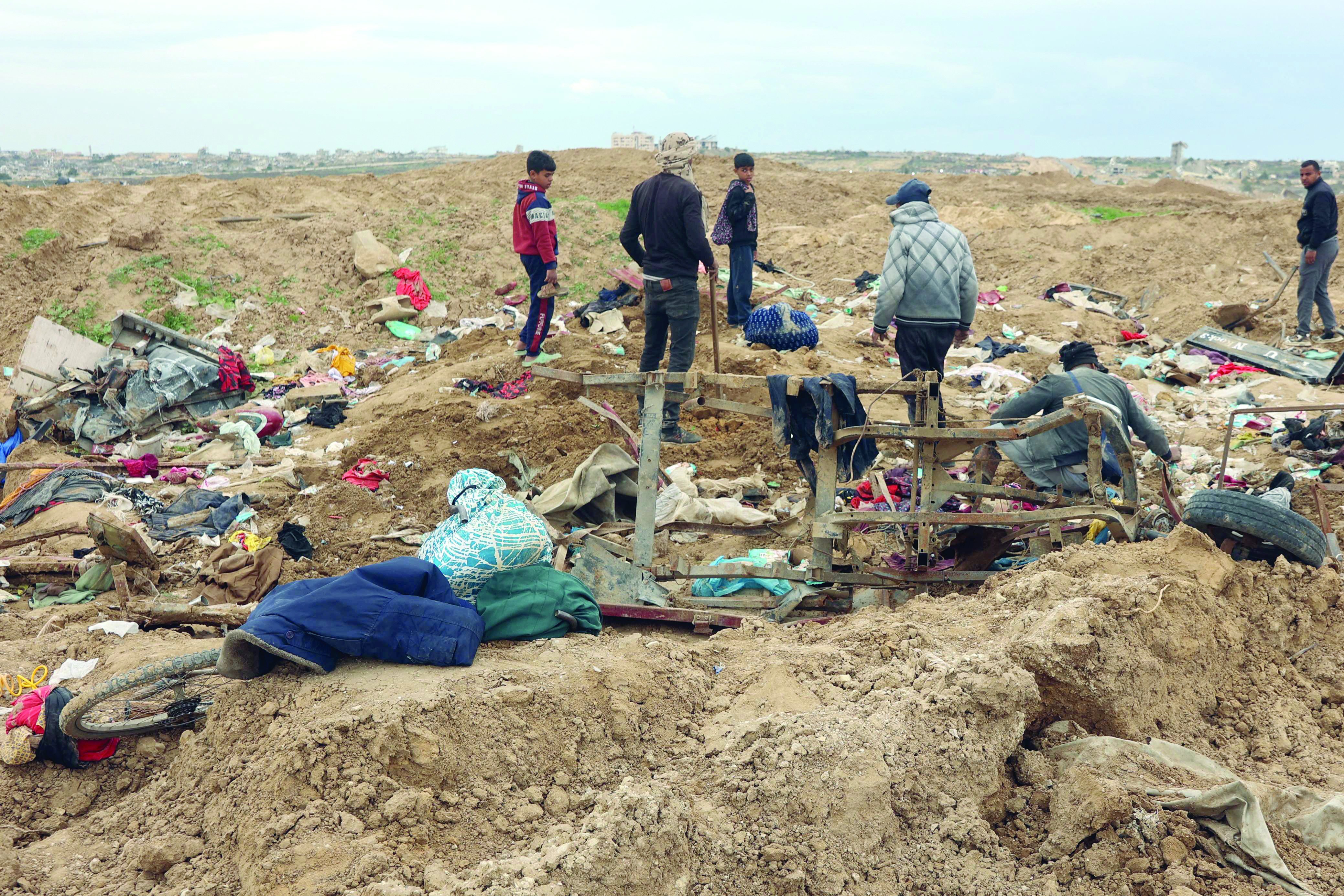 displaced palestinians inspect piles of clothes as they cross the netzarim corridor and make their way to the northern parts of the gaza strip photo afp