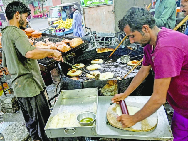 vendors prepare khajla a traditional dessert commonly consumed during ramazan at a shop in karachi on the eve of the holy month this crispy deep fried delicacy is a staple for sehri often enjoyed with milk or added to various sweet dishes photo afp
