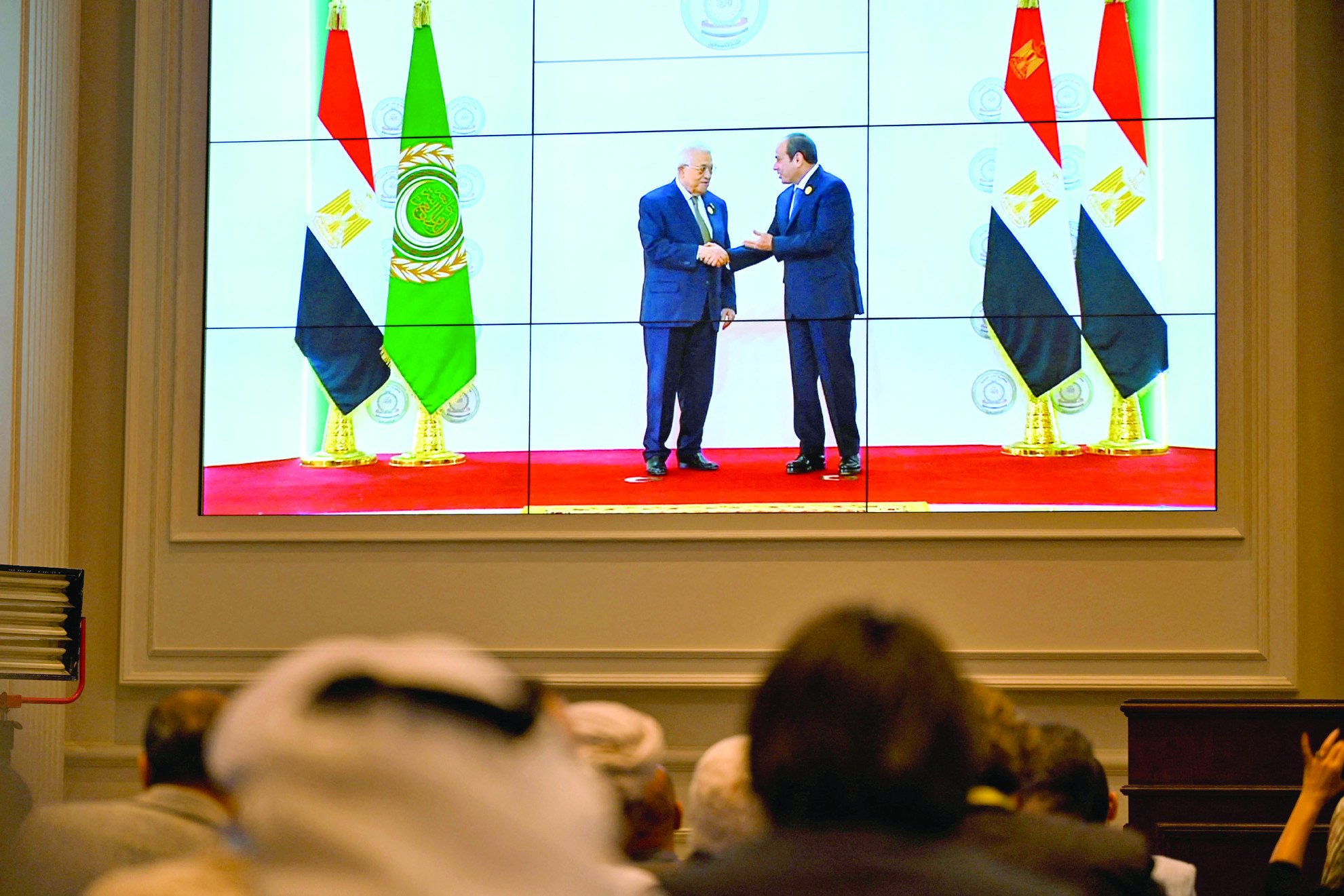 people watch on a big screen as egypt s president abdel fattah al sisi welcomes palestinian president mahmud abbas photo afp