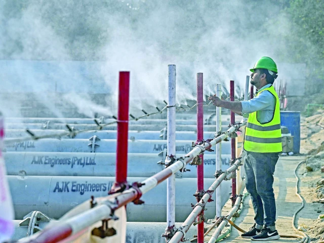 a worker adjusts an anti smog dust suppression sprayer installed at a construction site in lahore photo afp a worker adjusts an anti smog dust suppression sprayer installed at a construction site in lahore photo afp
