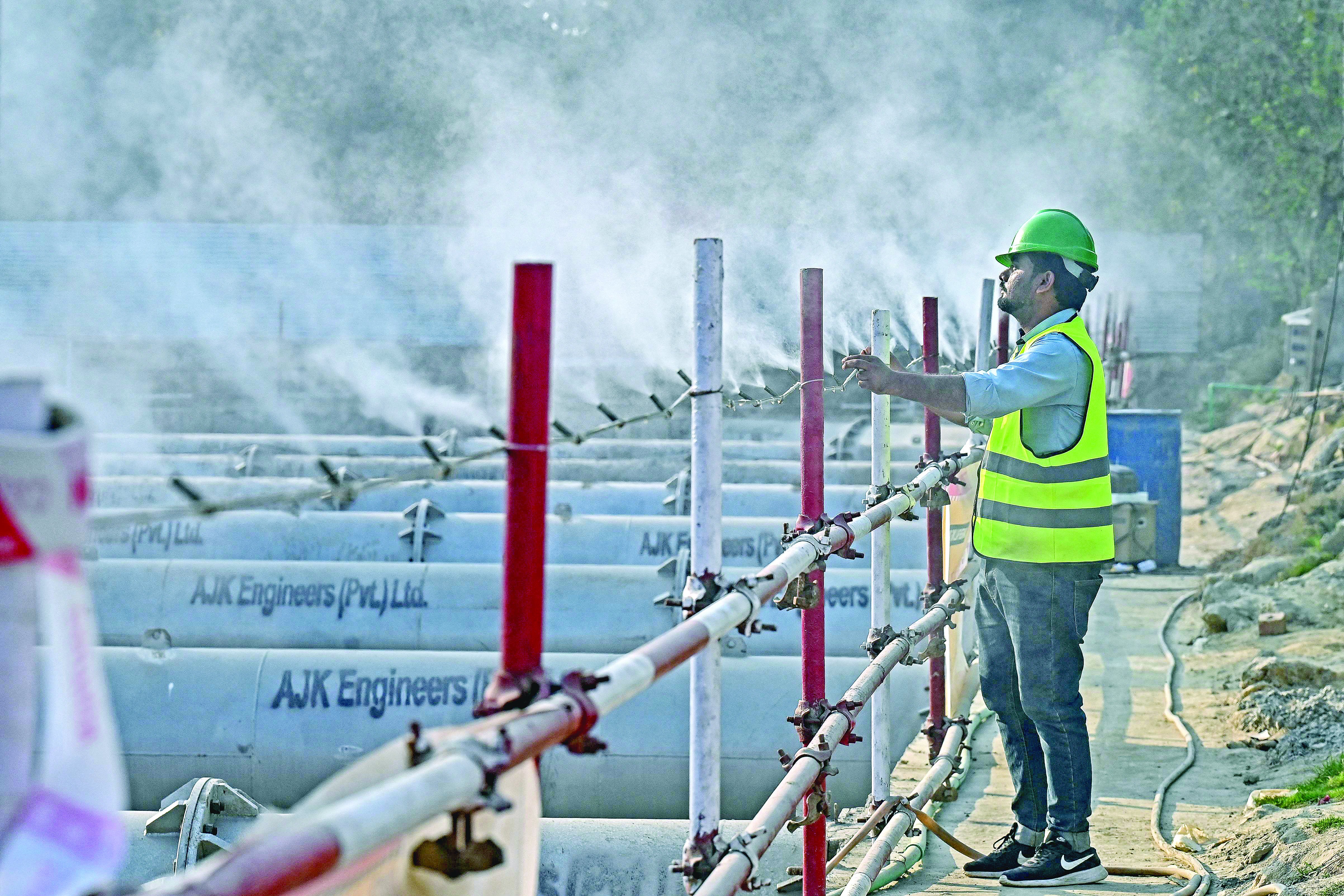 a worker adjusts an anti smog dust suppression sprayer installed at a construction site in lahore photo afp