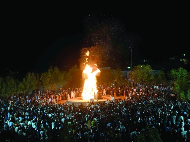 hindu community members gather around a bonfire as they celebrate the festival of colours in mithi photo afp