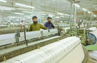 workers inspect loom machines weaving fabric at a textiles manufacturer in karachi photo reuters