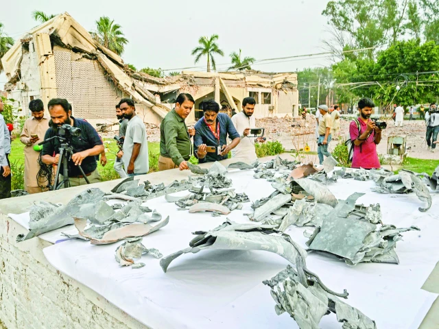 journalists look at the shards of indian missiles that hit the government health and educational complex in muridke photo afp journalists look at the shards of indian missiles that hit the government health and educational complex in muridke photo afp