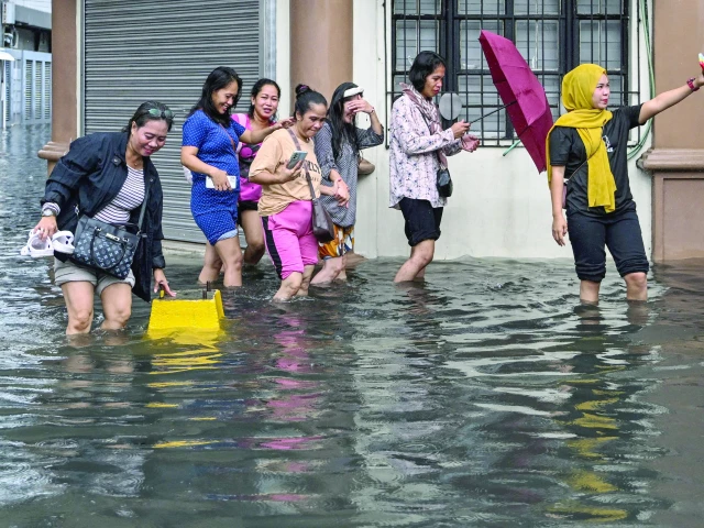a woman poses for a selfie while wading with others through a street in manila after heavy rains caused flooding photo afp a woman poses for a selfie while wading with others through a street in manila after heavy rains caused flooding photo afp
