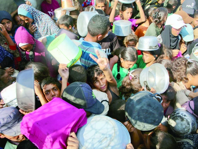 a palestinian boy flashes the victory sign as he shoves the crowd to receive a hot meal at a charity kitchen in the mawasi area of khan yunis in gaza strip photo afp
