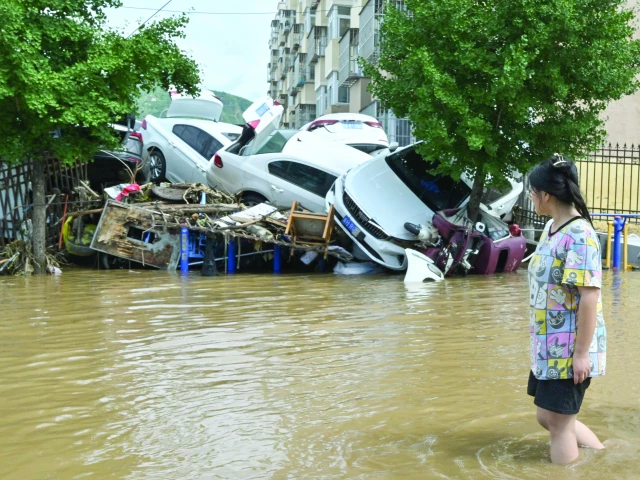a woman walks past damaged cars in a flooded neighbourhood in beijing s miyun district photo afp a woman walks past damaged cars in a flooded neighbourhood in beijing s miyun district photo afp