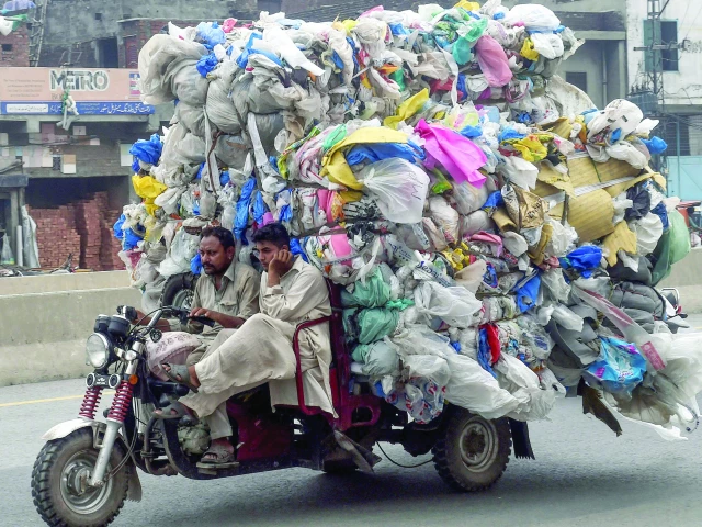 a man drives a three wheeler loaded with used plastic bags in lahore photo afp