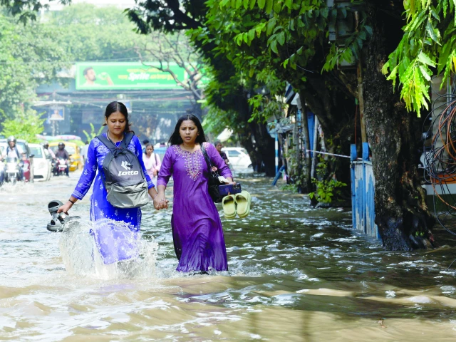 people wade through a waterlogged street in kolkata photo reuters