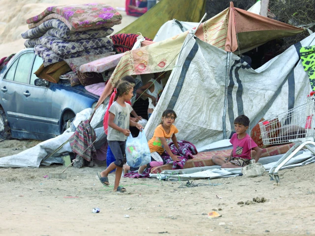 displaced palestinians sit next to a tent in the central gaza strip photo reuters