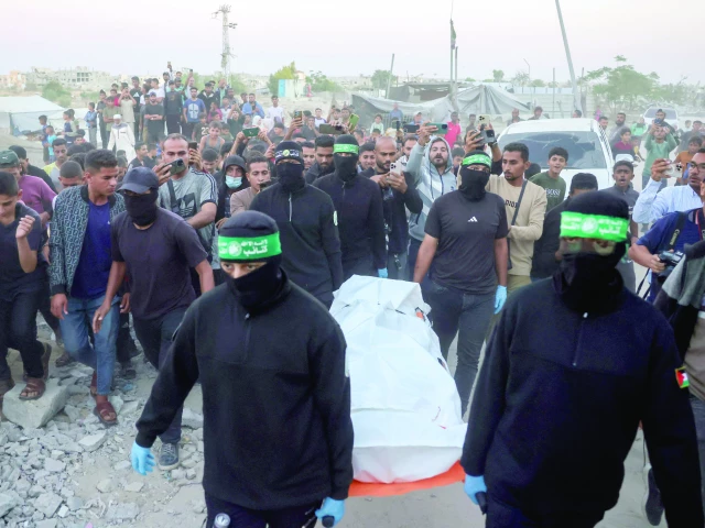 people look on as hamas fighters carry a body retrieved from a tunnel in an area north of khan yunis photo afp