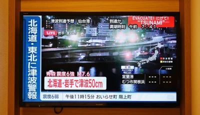 a tsunami warning flashes over live footage of a waterfront area on a television screen in sapporo in japan s northern hokkaido prefecture on december 9 2025 photo afp