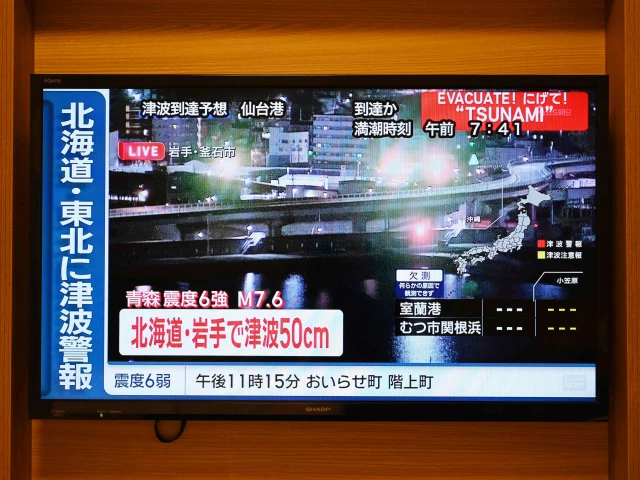 a tsunami warning flashes over live footage of a waterfront area on a television screen in sapporo in japan s northern hokkaido prefecture on december 9 2025 photo afp