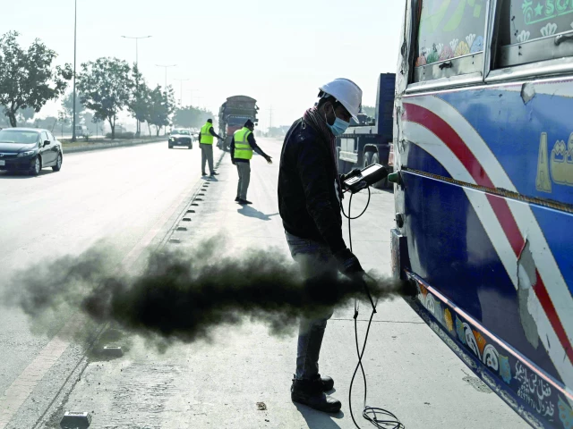 a technician examines a vehicle to test its emissions on a road on the outskirts of islamabad photo afp a technician examines a vehicle to test its emissions on a road on the outskirts of islamabad photo afp