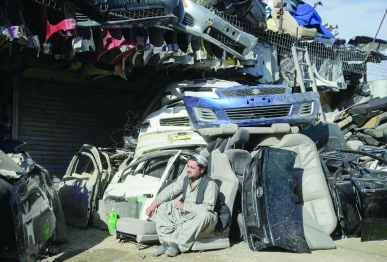 a man sits outside an auto parts shop at a market near the zero point border crossing between afghanistan and pakistan photo afp