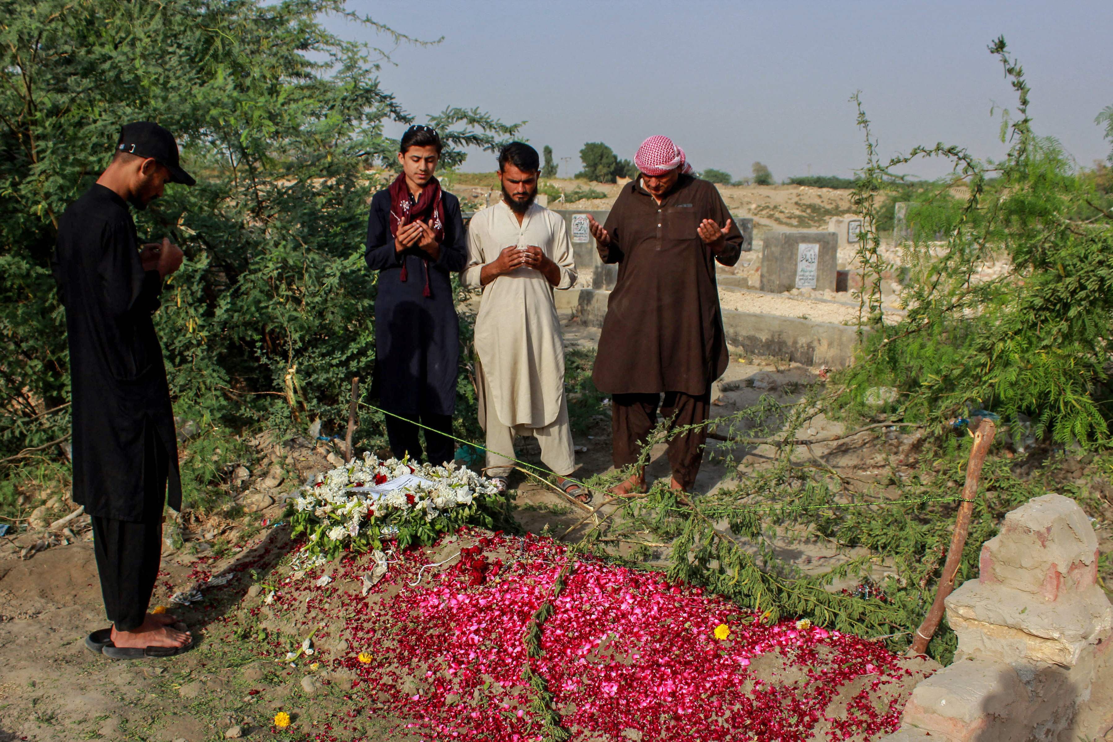Relatives offer prayers on the grave of Pakistani national Muzaffar Ali, who was killed in Dubai amid the ongoing Middle East war, after his funeral in Jamshoro in Sindh province on March 12, 2026. PHOTO: AFP