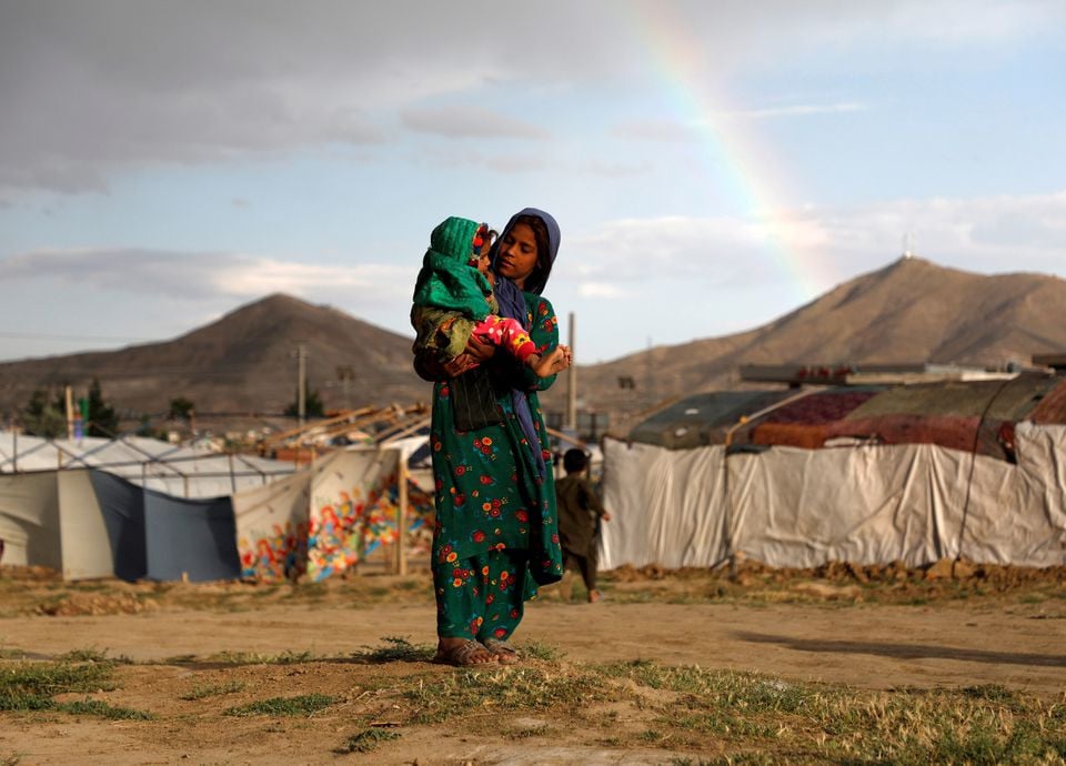 an internally displaced afghan girl carries a child near their shelter at a camp on the outskirts of kabul afghanistan june 20 2019 photo reuters