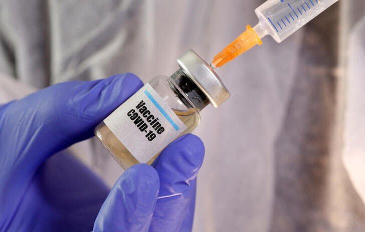 a woman holds a small bottle labeled with a vaccine covid 19 sticker and a medical syringe in this illustration taken april 10 2020 photo reuters