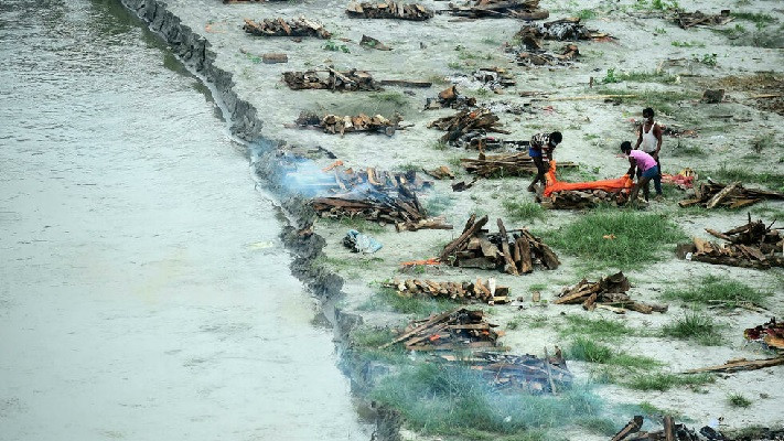 municipal corporation workers prepare to cremate a body buried in a shallow grave on the banks of the ganges river during the covid 19 pandemic photo afp