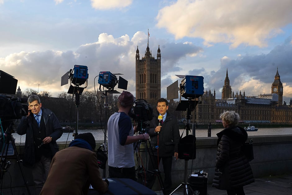 Television journalists stand on the bank of the River Thames as they broadcast opposite the Houses of Parliament in Westminster, central London. PHOTO: AFP