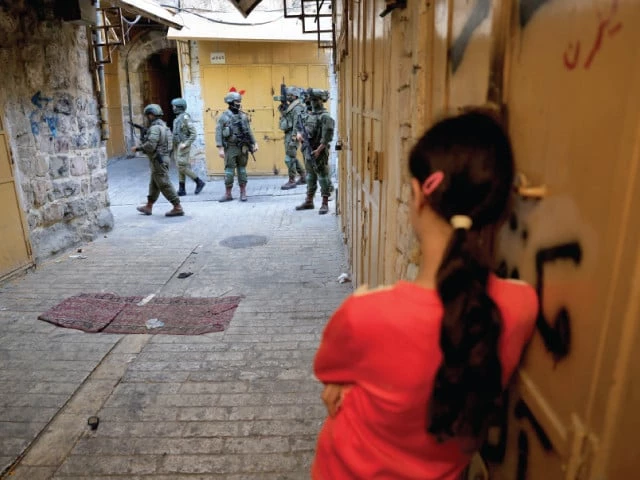 a palestinian girl waits to pass as israeli settlers take part in a weekly tour in hebron in the israeli occupied west bank photo reuters a palestinian girl waits to pass as israeli settlers take part in a weekly tour in hebron in the israeli occupied west bank photo reuters