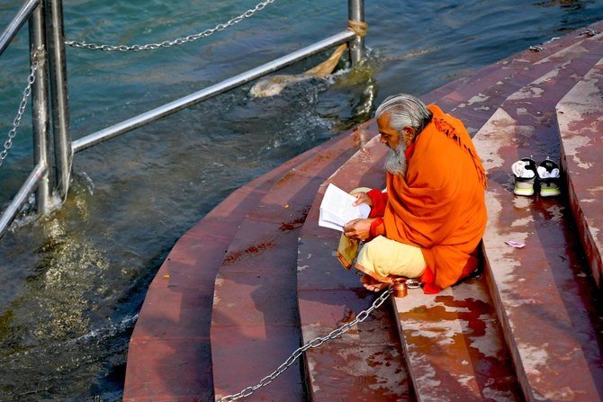 a hindu holyman reads at a ghat of the river ganges ahead of their religious kumbh mela festival in haridwar on january 13 2021 afp