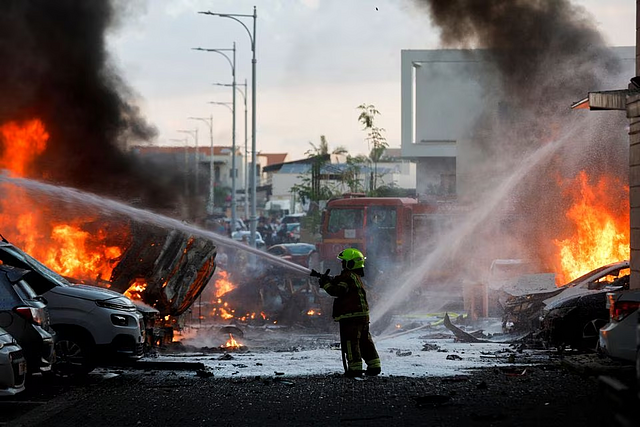 An emergency personnel works to extinguish the fire after rockets are launched from the Gaza Strip, as seen from the city of Ashkelon, Israel October 7: REUTERS