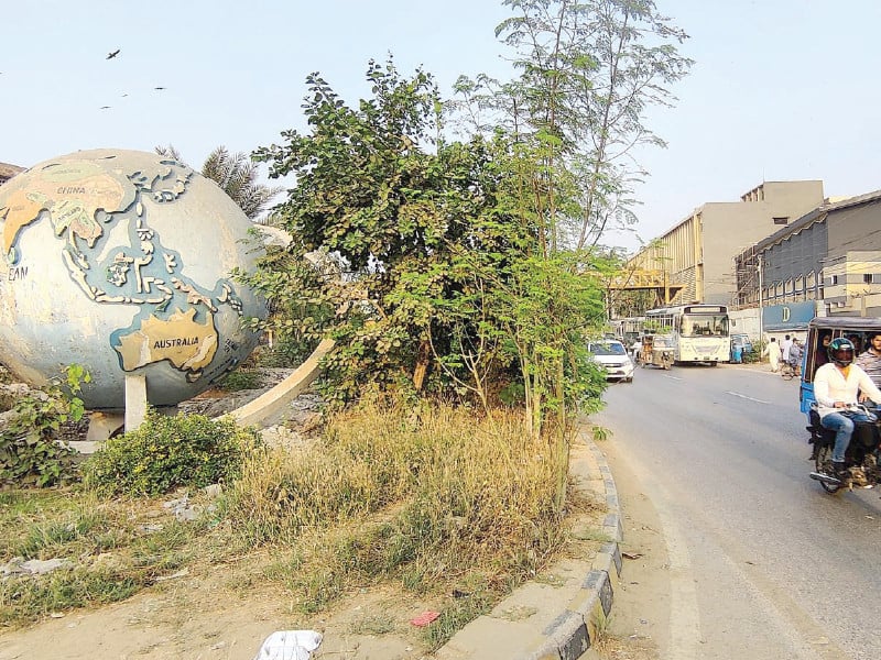 bushes have grown around the model of the globe on new ma jinnah road tmc jinnah town plans to relocate the landmark to statdium road to escape eminent demolition due to brt construction photo inp