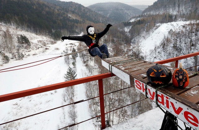 a member of the exit point amateur rope jumping group wearing a halloween mask jumps from a 44 metre high 144 ft water pipe bridge to mark the end of the group s jumping season and recent halloween festivities in the siberian taiga area outside krasnoyarsk russia photo reuters