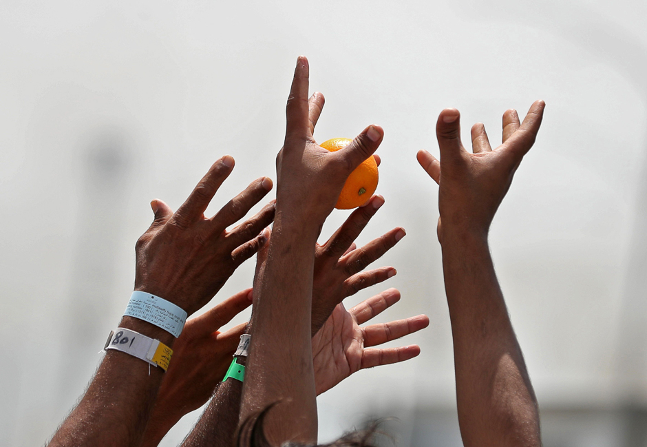 Pilgrims reach up to receive food donations near Mount Arafat. PHOTO: AFP