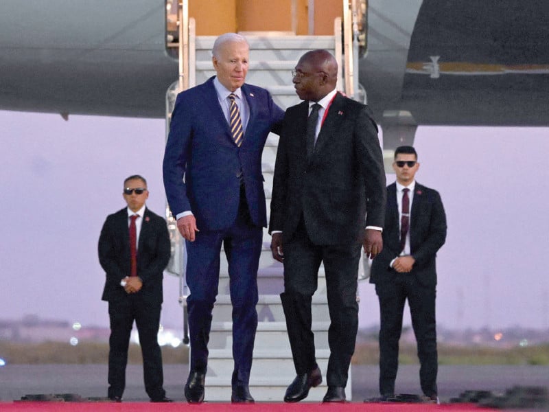 us president joe biden walks on the red carpet next to foreign affairs minister tete antonio upon his arrival in angola photo afp