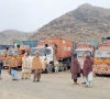 people stand next to parked trucks loaded with supplies at the torkham border crossing following a clash between pakistan and afghanistan photo reuters